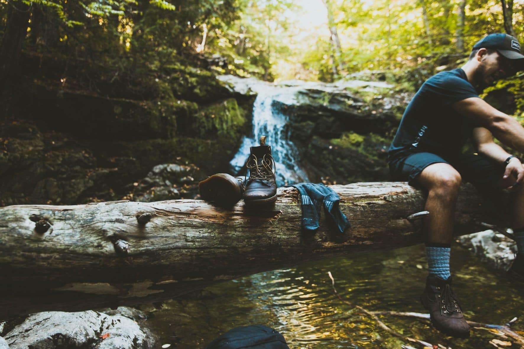 Mann macht eine Wander-Pause an einem Bach 