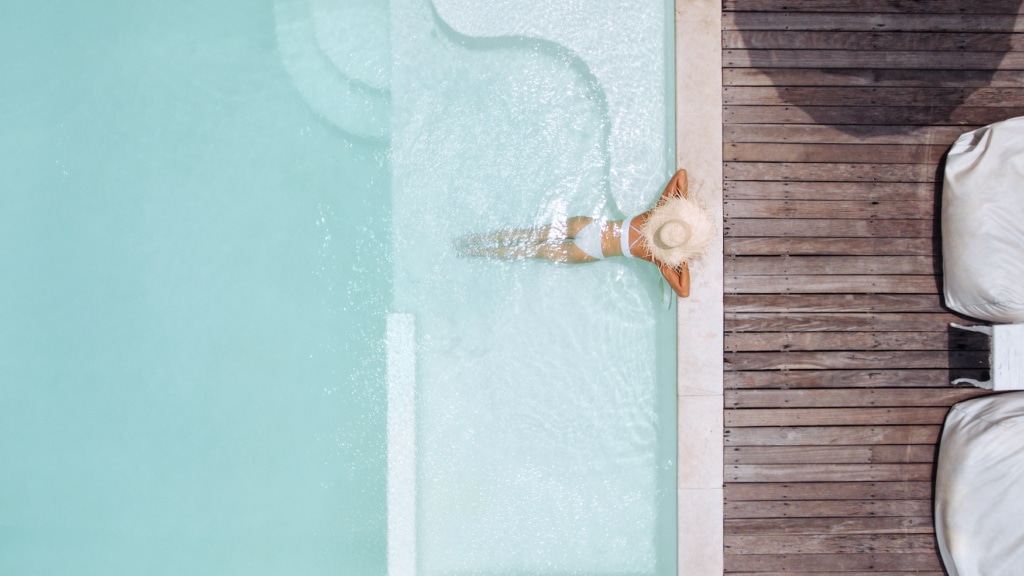 Frau mit Strohhut entspannt in einem Pool einer Traumvilla