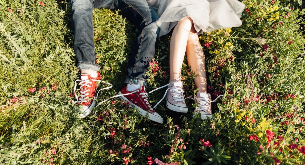 Pärchen mit Converse liegt im Gras