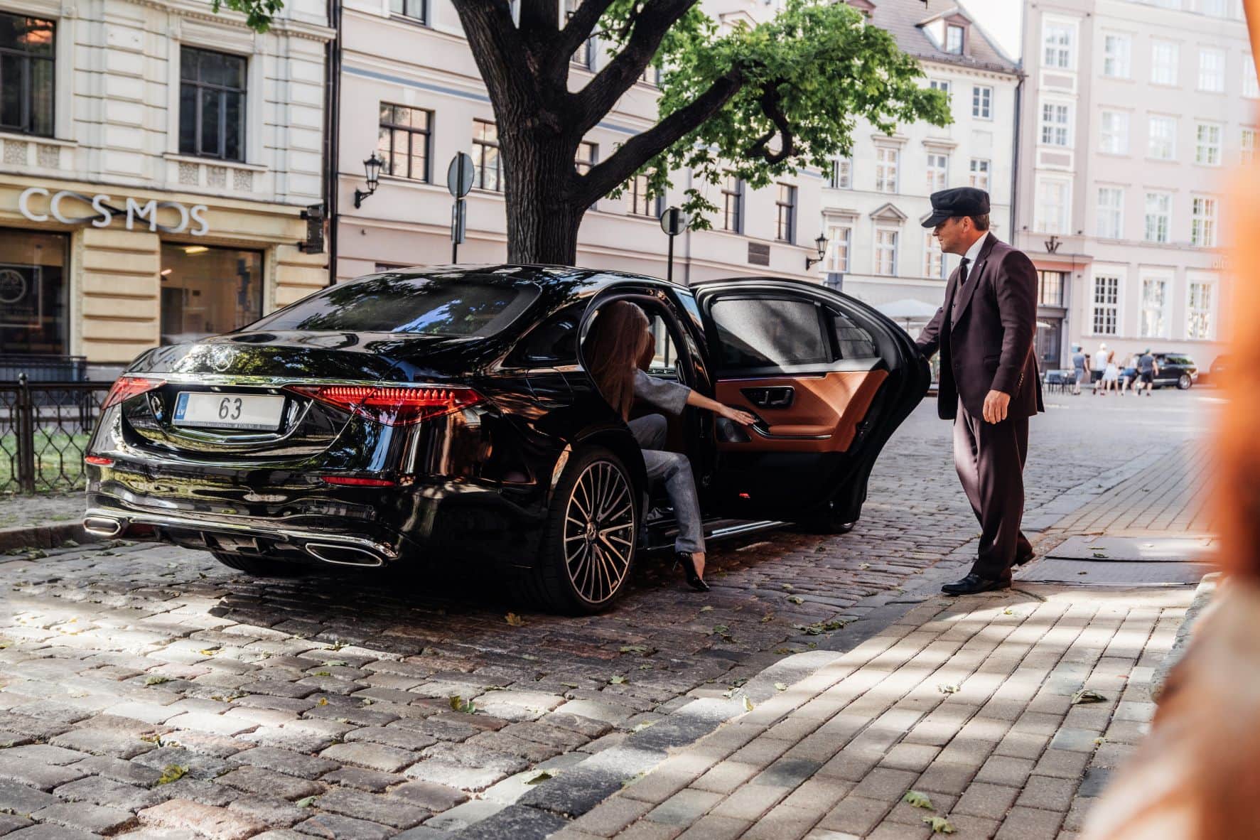 Frau steigt aus Luxusauto, Portier hält die Tür auf