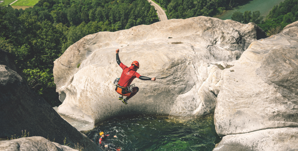 Mann springt von einem Felsen in ein Wasserbecken.