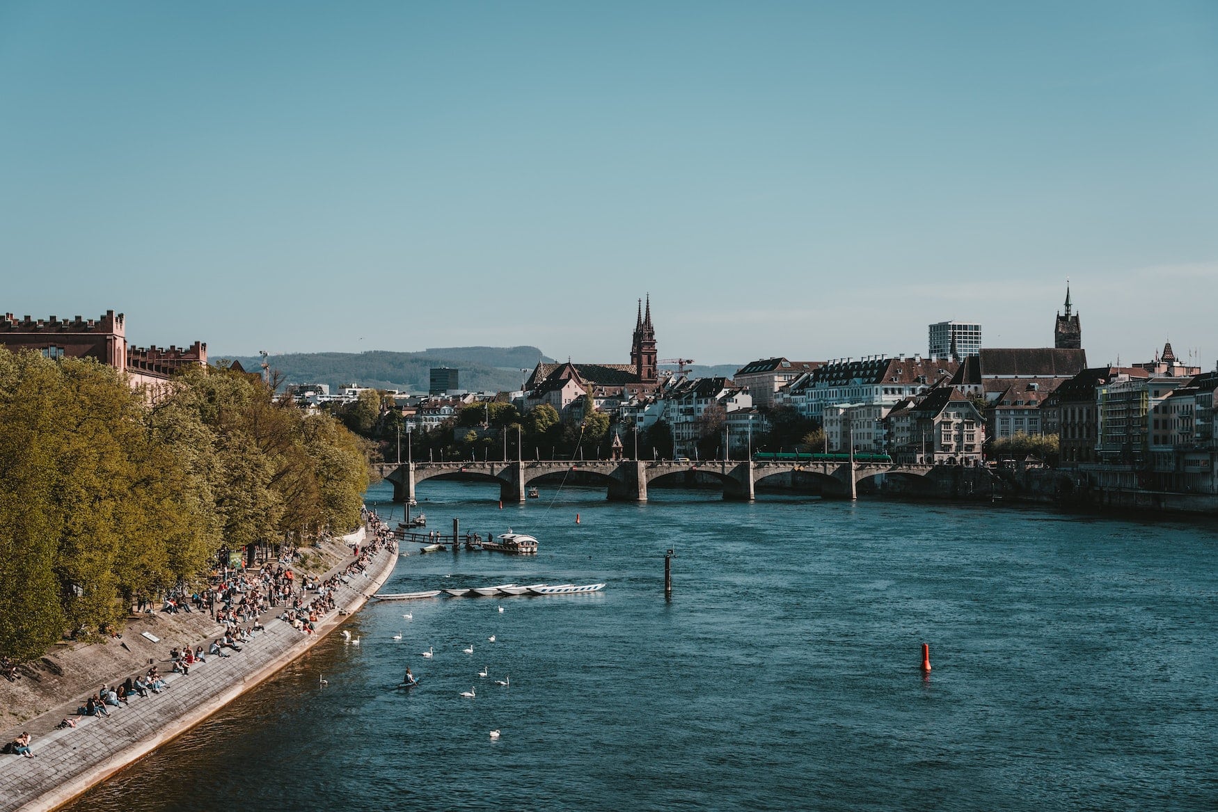 Junge Menschen sitzen am Rhein in Basel