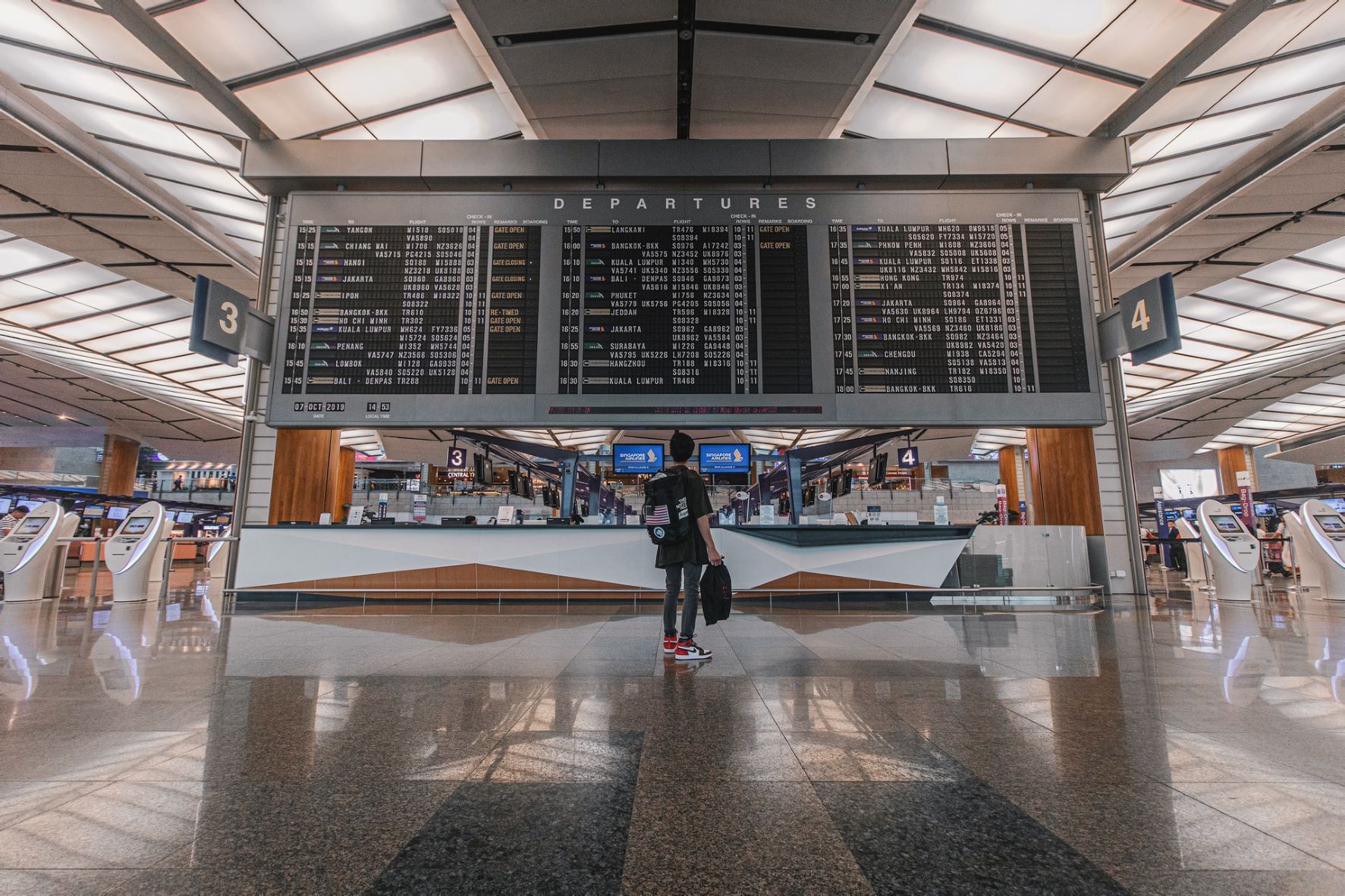 Frau blickt auf Anzeigetafel für Abflüge im Flughafen