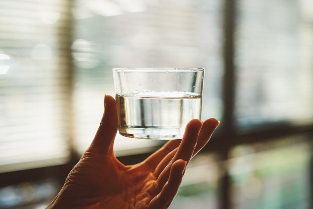 Hand hält Glas Wasser