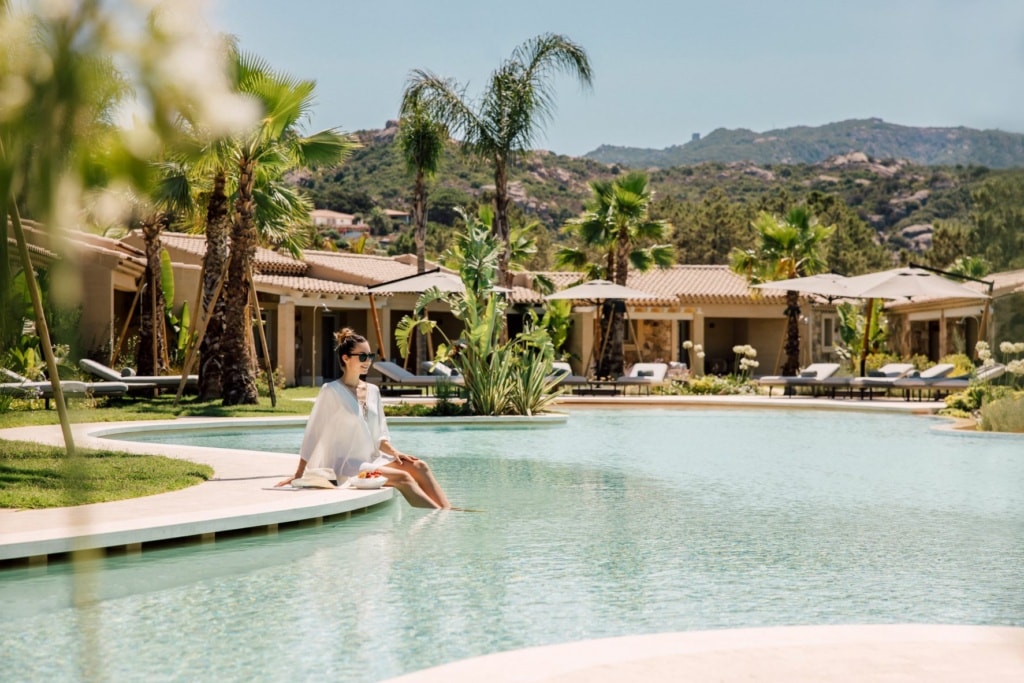 Frau sitzt am Pool des 7 Pines Resort Sardinia