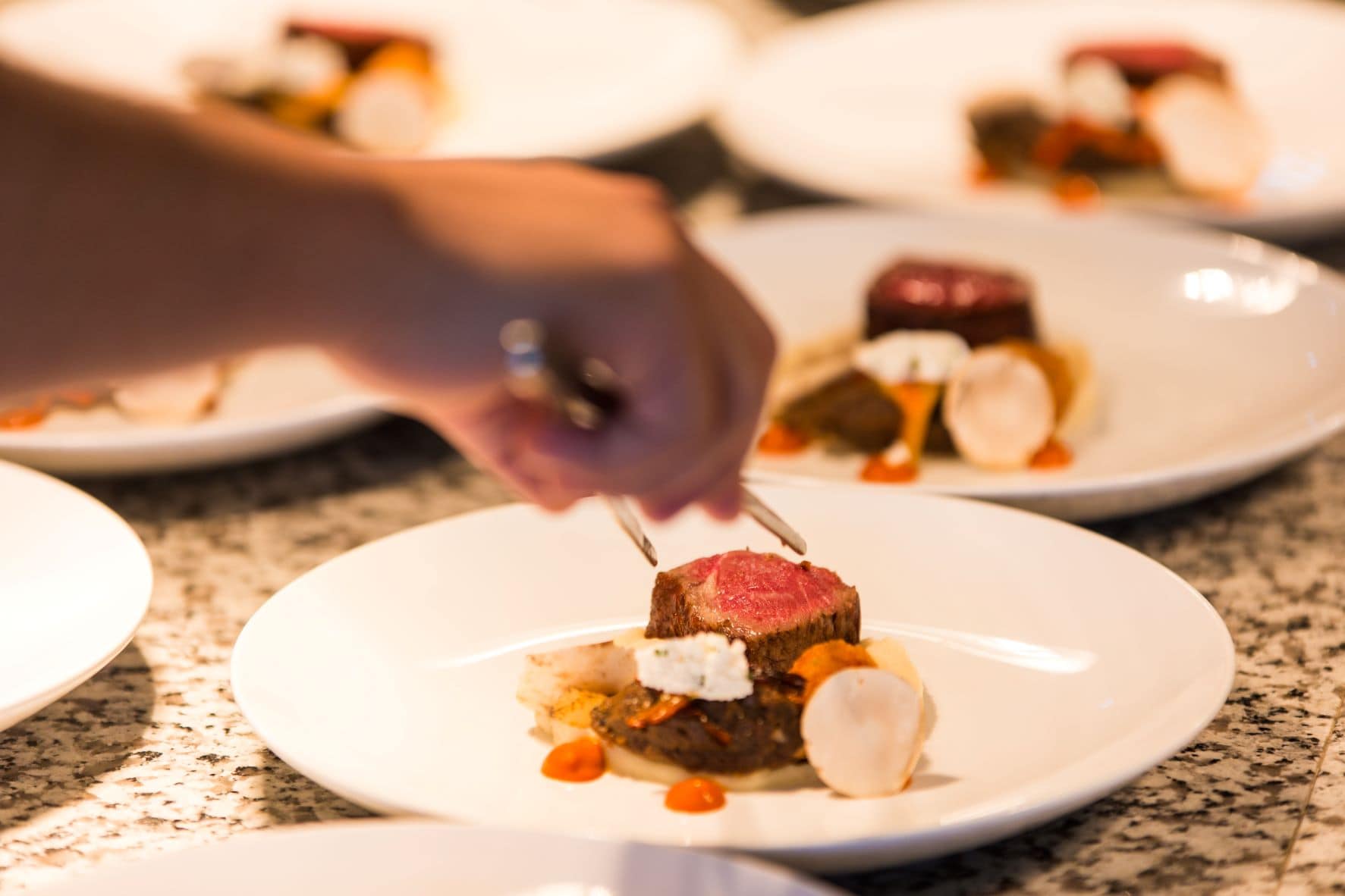 Haute Cuisine: Person richtet mit Zange Teller mit Rinderfilet an