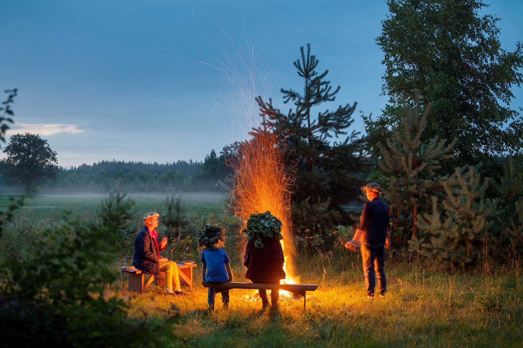 Familie sitzt in Mitsommernacht am Lagerfeuer in Lettland