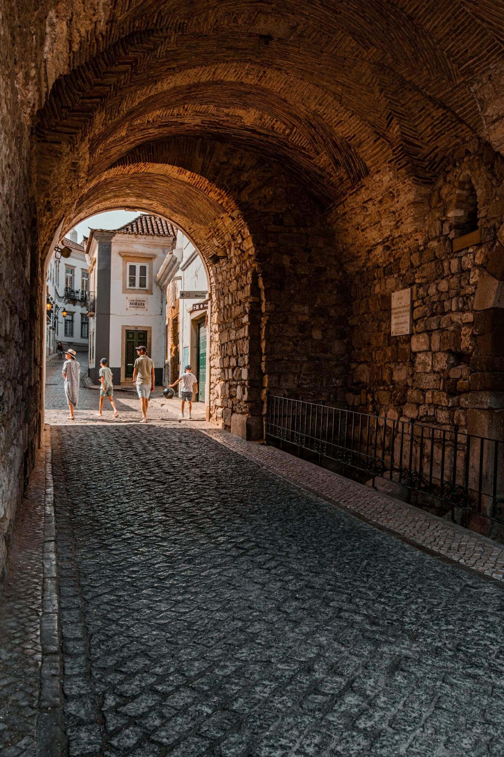 Familie spaziert durch Altstadt-Tor in Faro