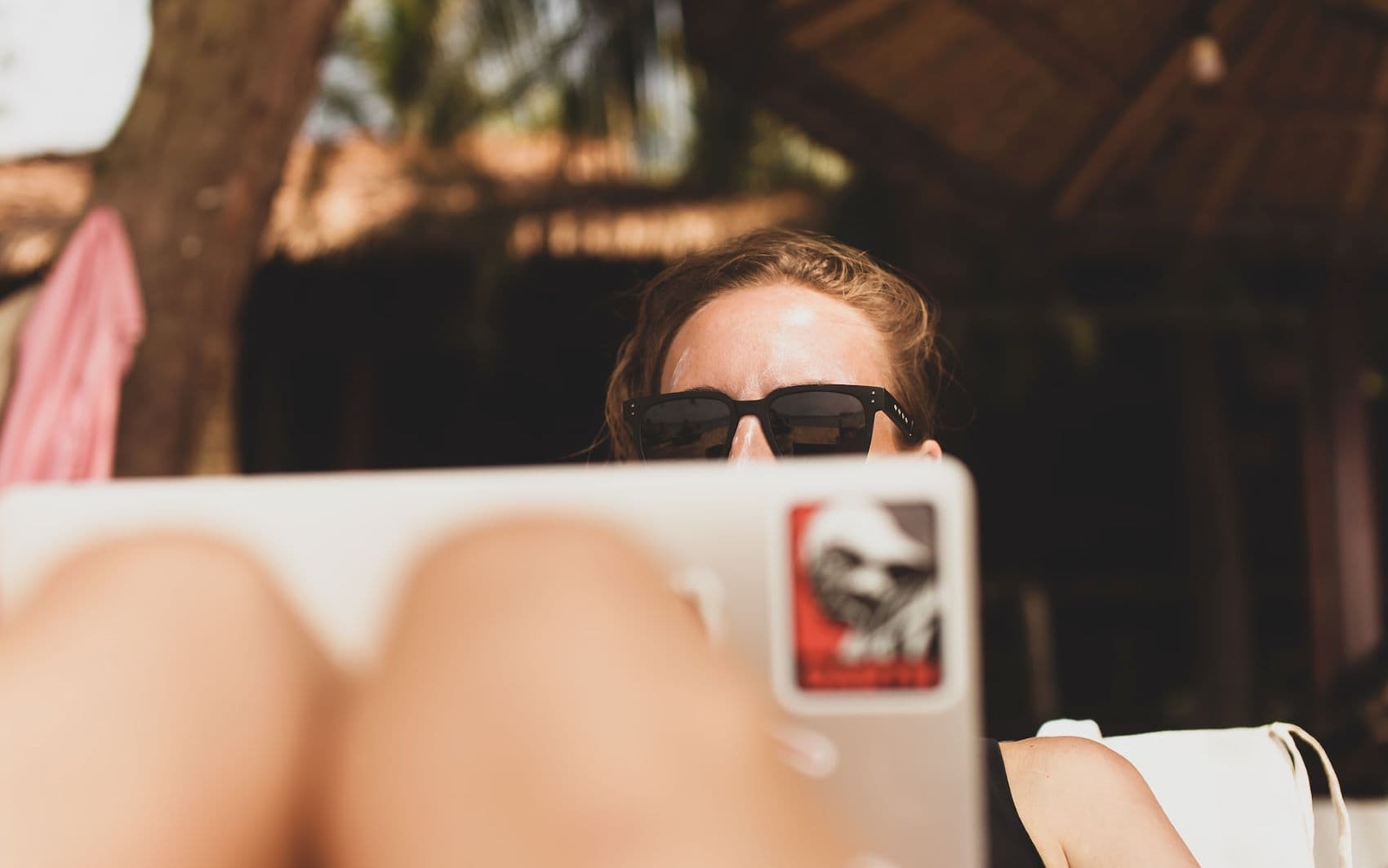 Frau mit Sonnenbrille am Notebook am Strand