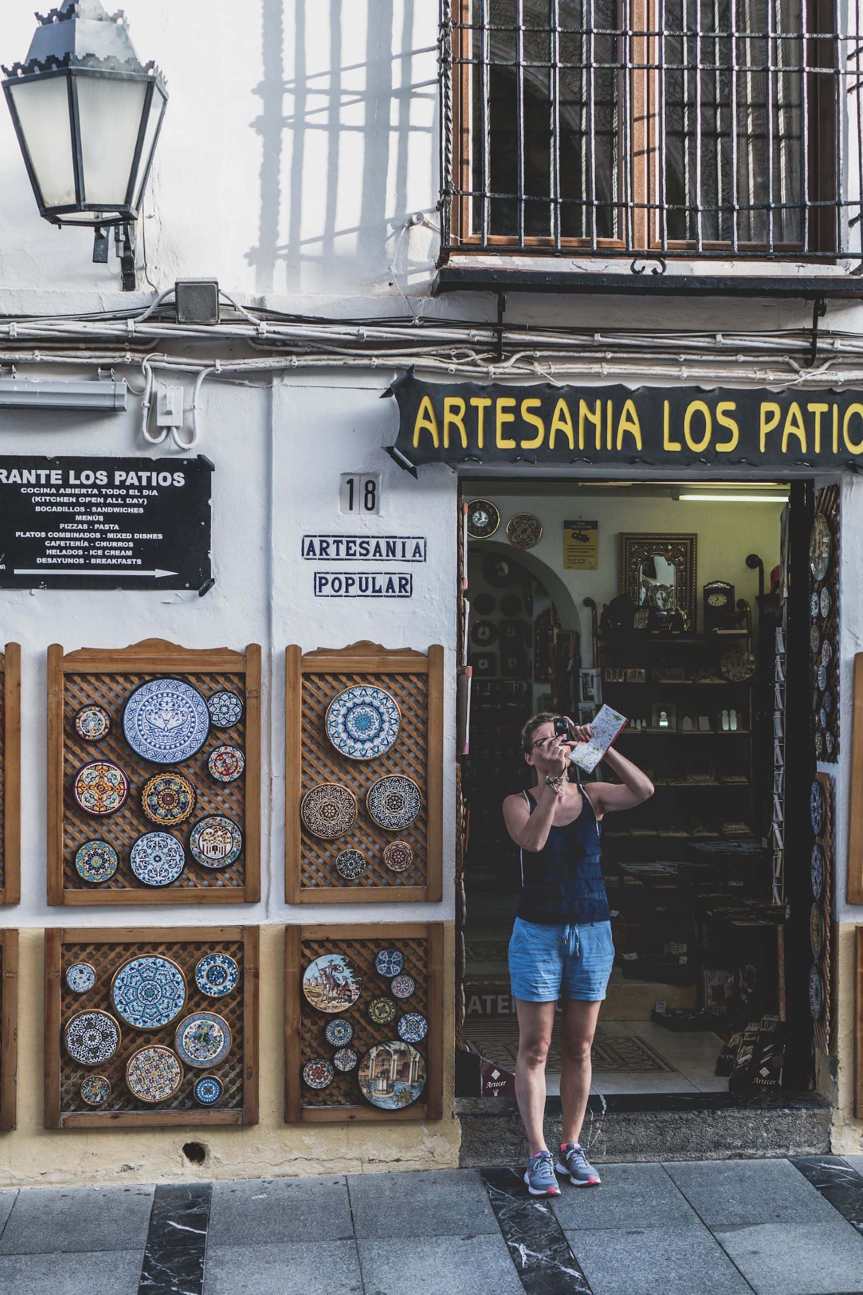 Frau macht Foto vor Kunsthandwerkshop in Cordoba