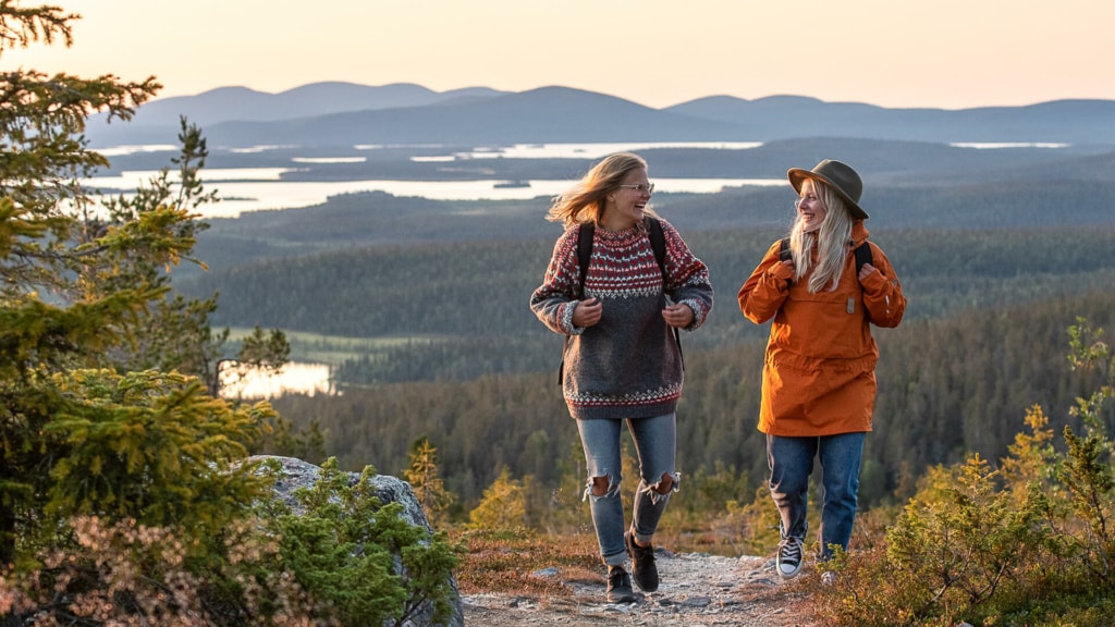 Zwei Wanderinnen unterhalten sich auf einem Trail, im Hintergrund sieht man den Pallas-Ylläs-Nationalpark in Lappland.