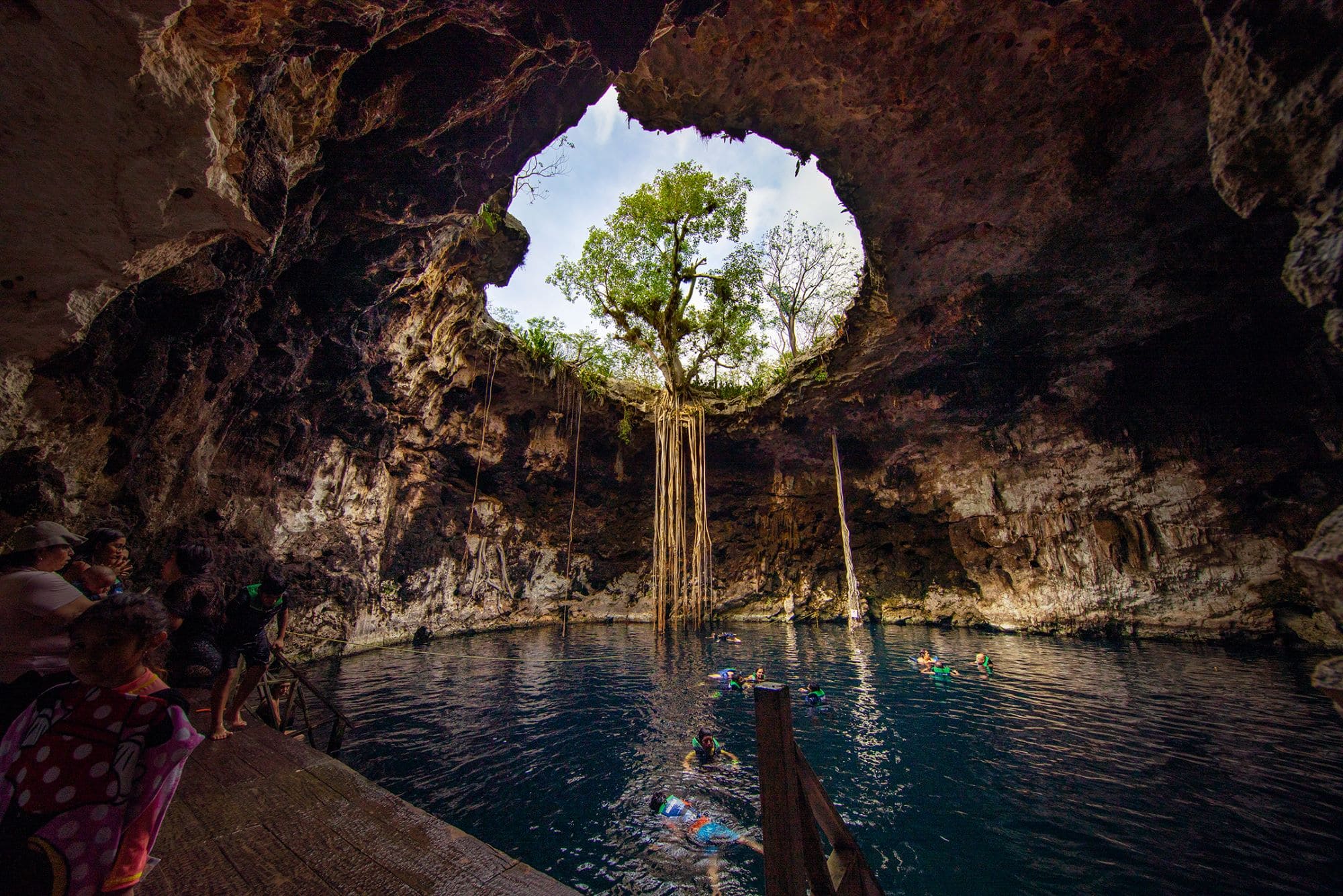 Menschen schwimmen in einer Cenote bei Sonnenschein in Mexiko