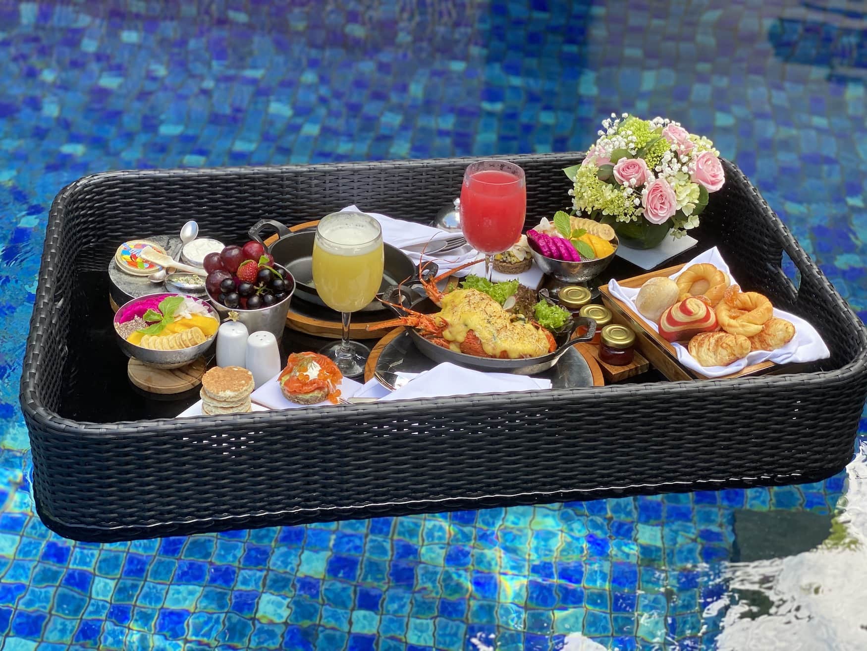Tablett voller Leckereien in einem Pool in Bali