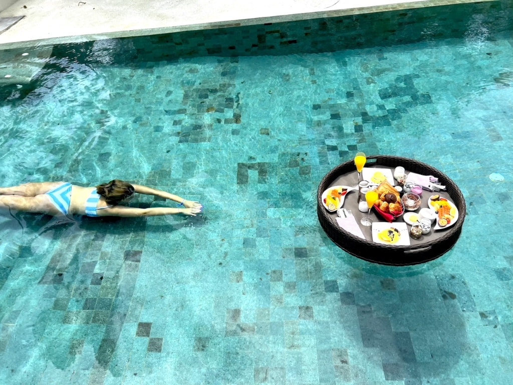 Frau schwimmt im Pool mit Floating Breakfast