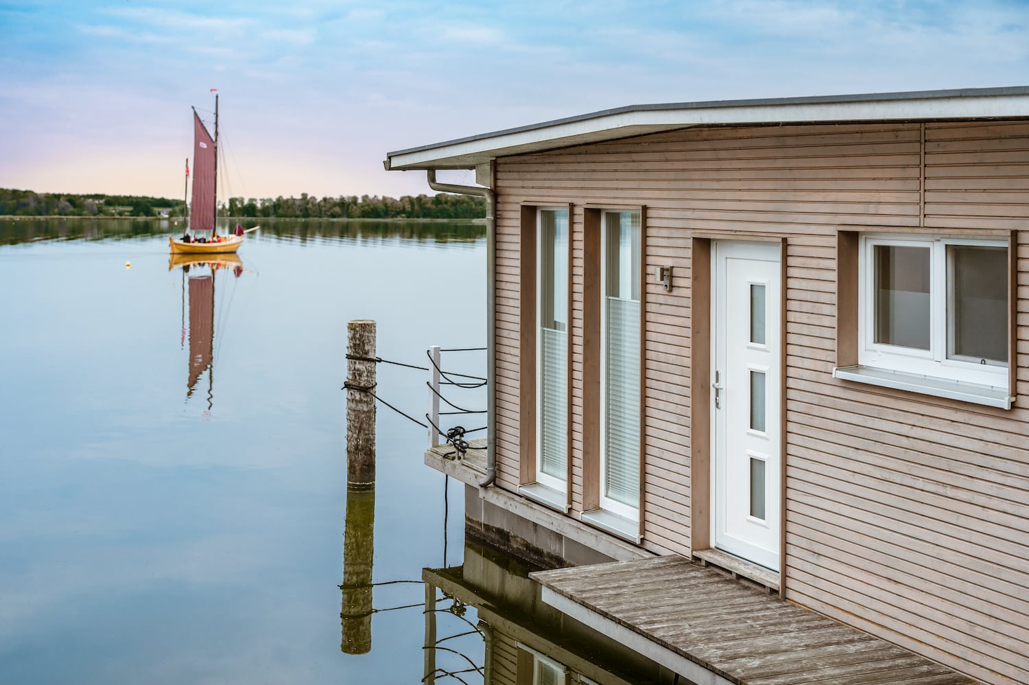 Schwimmendes Haus im Naturhafen Krummin mit einem Zeesboot im Hintergrund