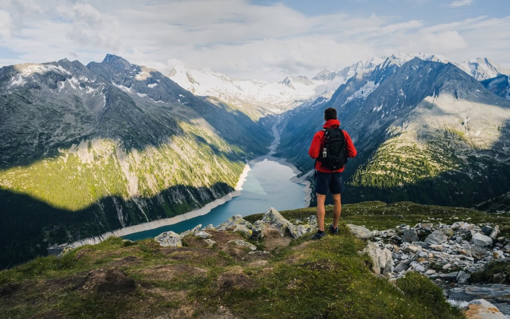 Mann wandert in den Alpen und genießt den Ausblick auf einen Bergsee