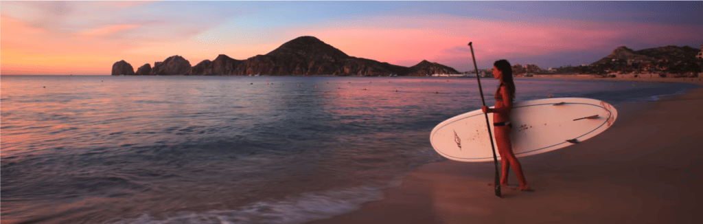 Frau mit Surfbrett am Medano Beach in Los Cabos