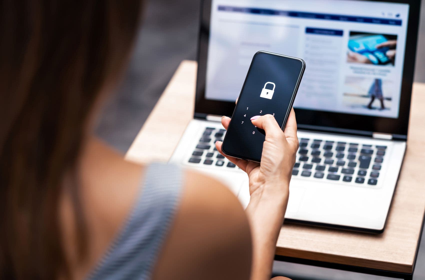 Frau mit Handy in der Hand vor Notebook