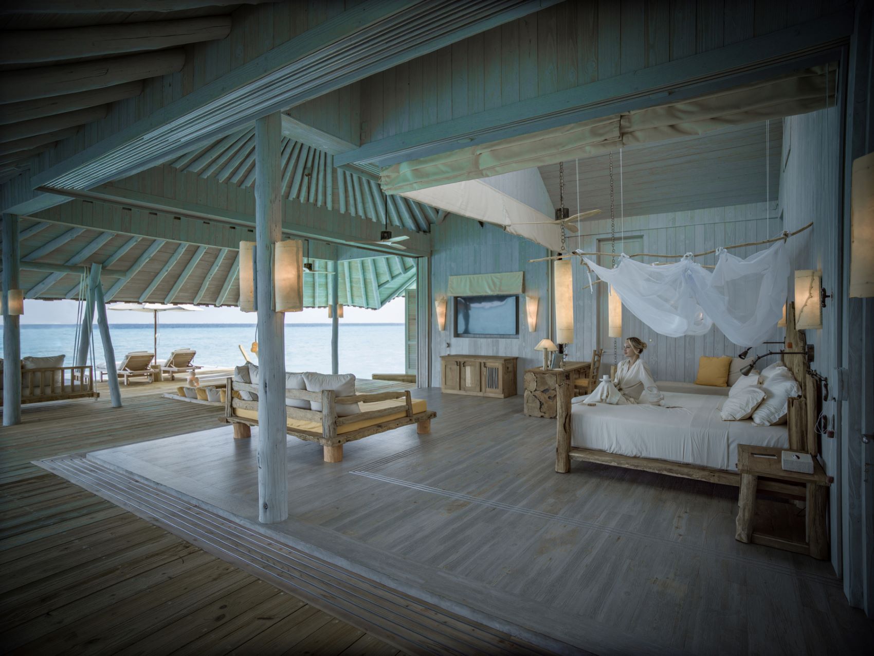 Frau auf Bett in Suite im Soneva Secret, Malediven