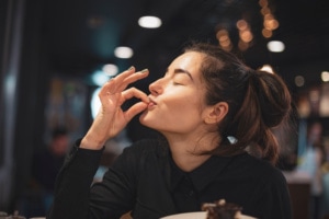Nahaufnahme einer Frau, die in einem Café Schokoladenkuchen isst.