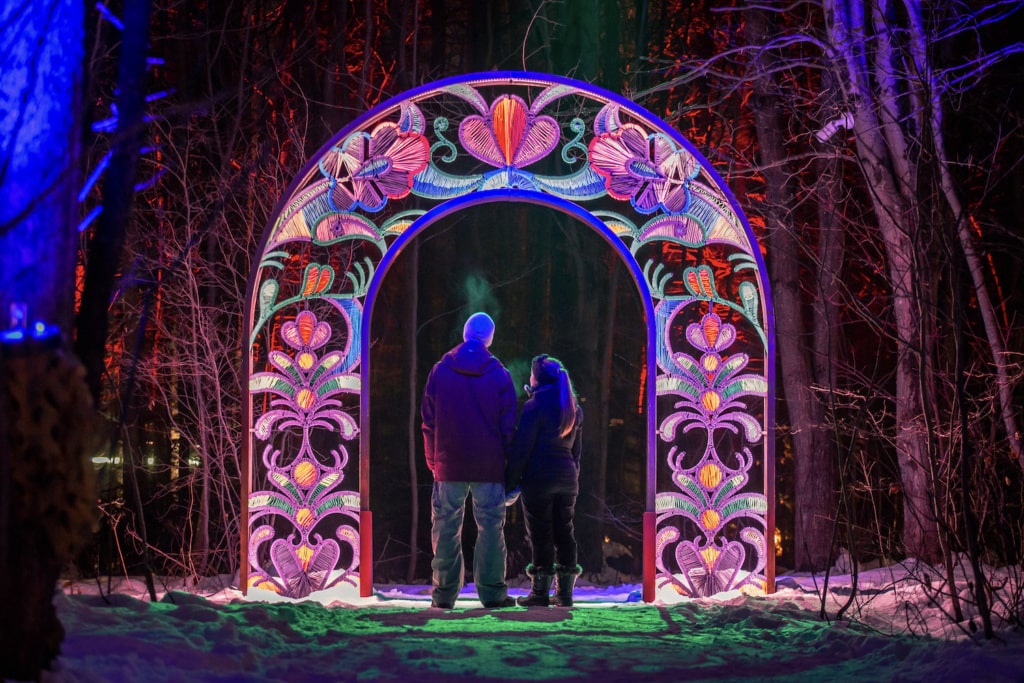 Zwei Personen stehen unter leuchtenem Torbogen bei dem Indigenen Erlebnis Onhwa’ Lumina in Kanada