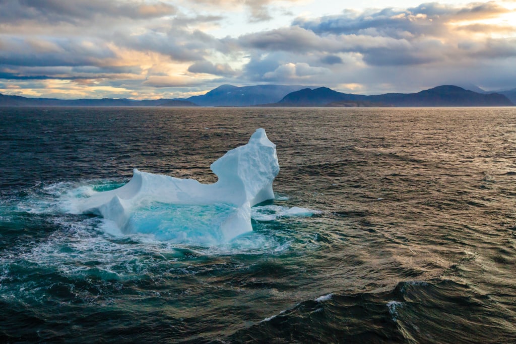 kleine Eisscholle im Wasser von Silouetten von Bergen im Torngat Nationalpark in Labrador, Kanada