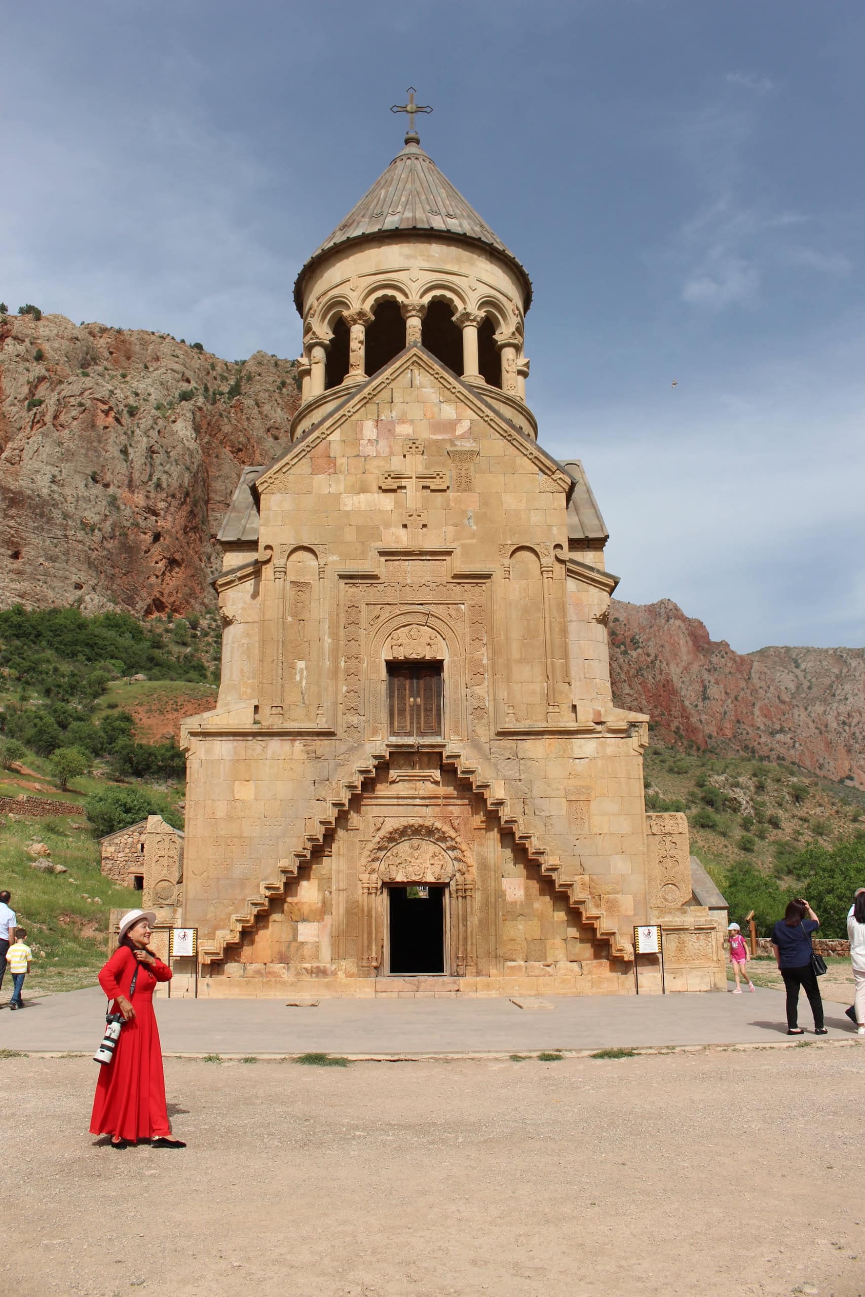 Kloster Norawank im Süden von Armenien, dahinter ein Felsmassiv; vor dem Eingang sind einige Menschen unterwegs