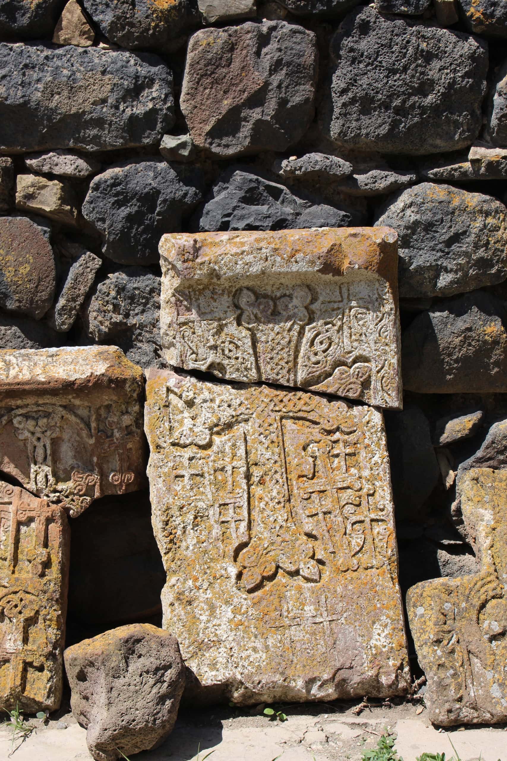 Nahaufnahme eines alten, gebrochenen Grabstein in Armenien, darauf ein armenisch-orthodoxes Kreuz eingraviert