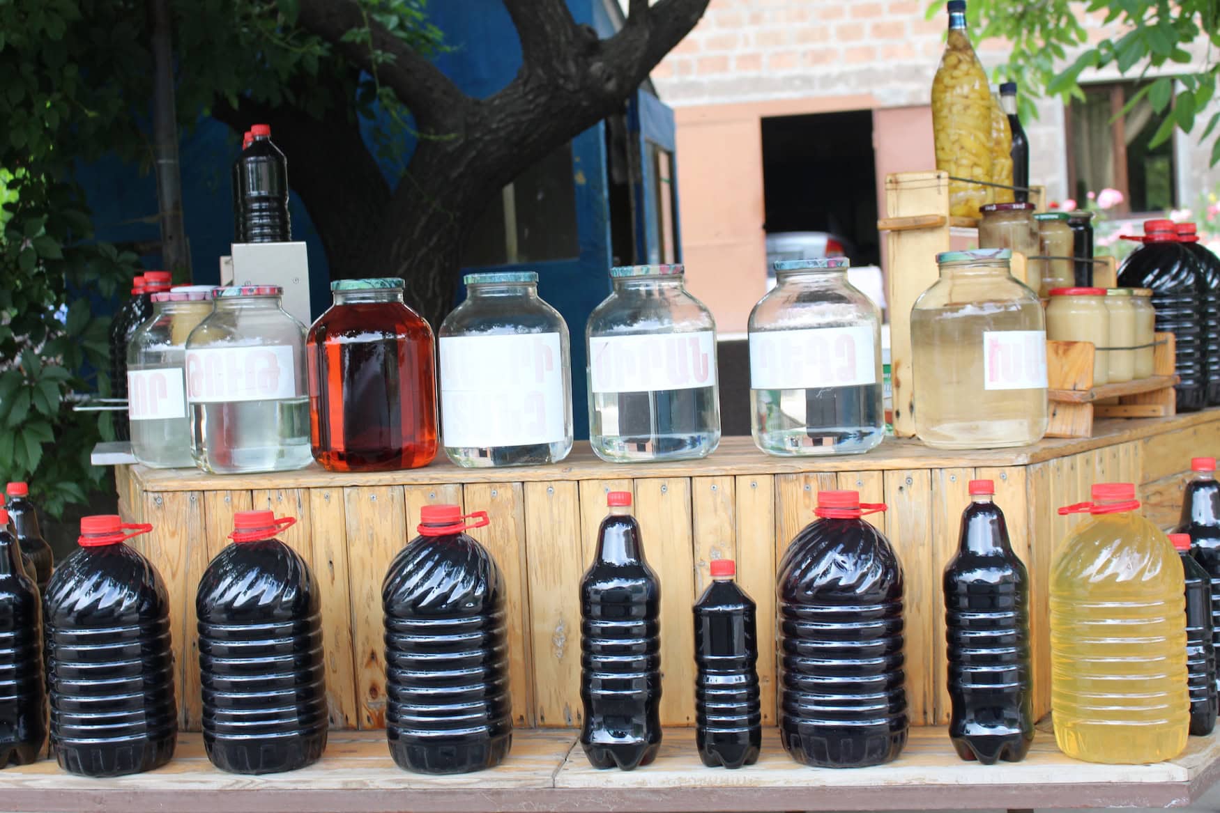 Auf einem improvisierten Regal stehen mehrere Flaschen armenische Cola – Wein in Plastikflaschen