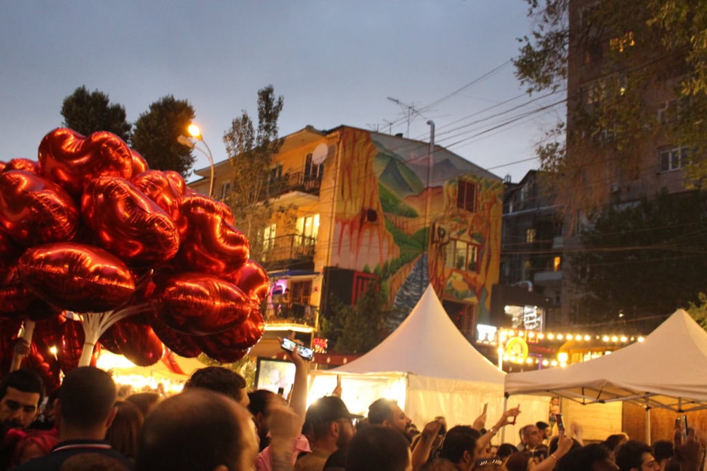 Yerevan Wine Days im Urlaub in Armenien; auf einer Straße zwischen einigen Wohnhäusern stehen zahlreiche weiße Pavillons, die Straße selbst ist gefüllt mit Menschen