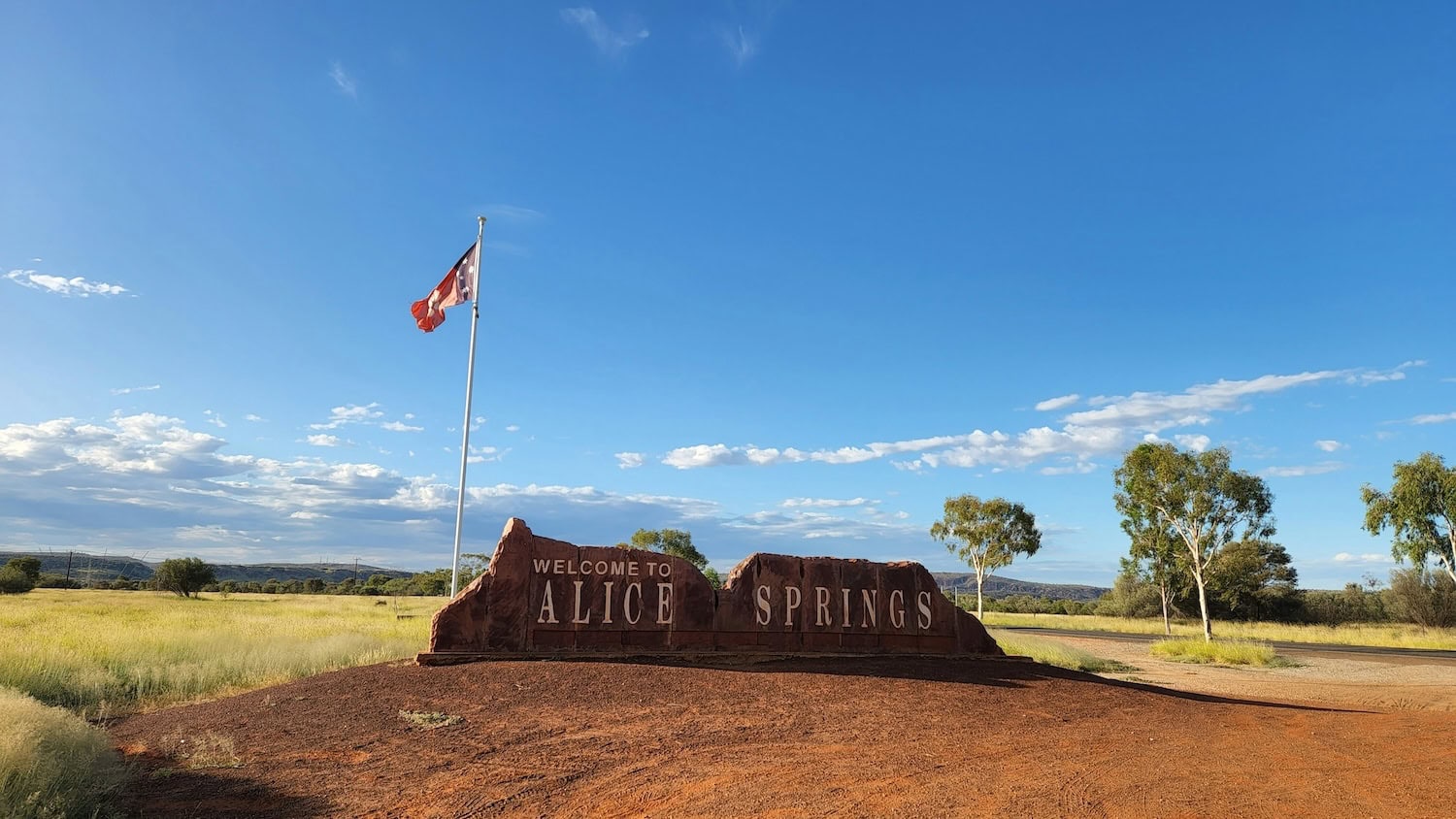 Schriftzug »Alice Springs« mit Flagge auf einem Felsen