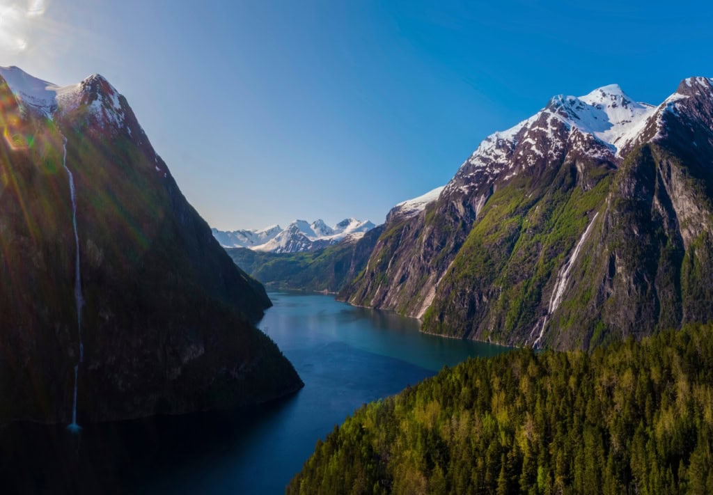 Zwischen zwei Gipfelketten in den Sunnmore-Bergen in Norwegen erstreckt sich im Licht der Sommersonne ein tiefblauer Fjord.