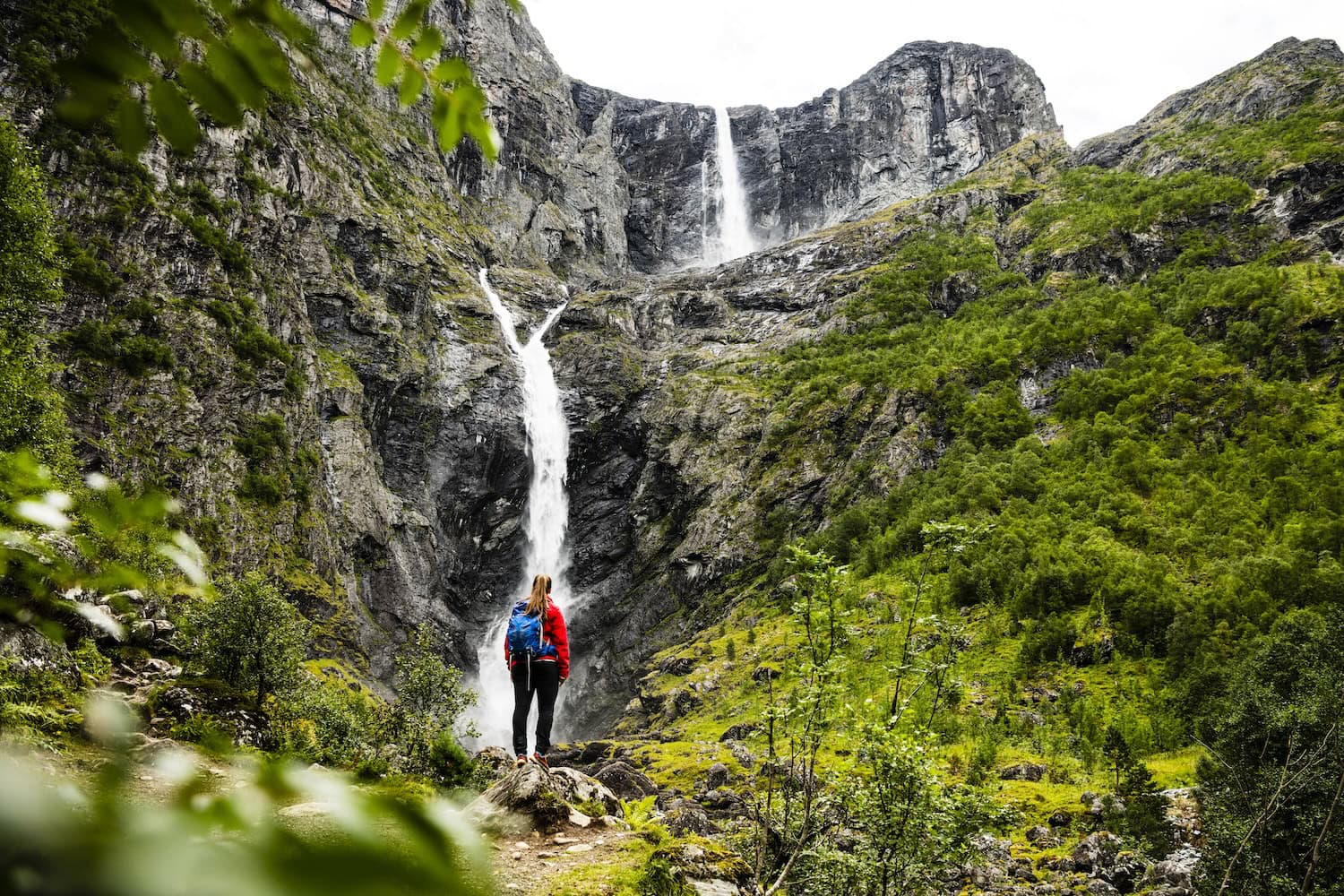 Eine Wanderin schaut auf den Mardalsfossen Wasserfall in Norwegen
