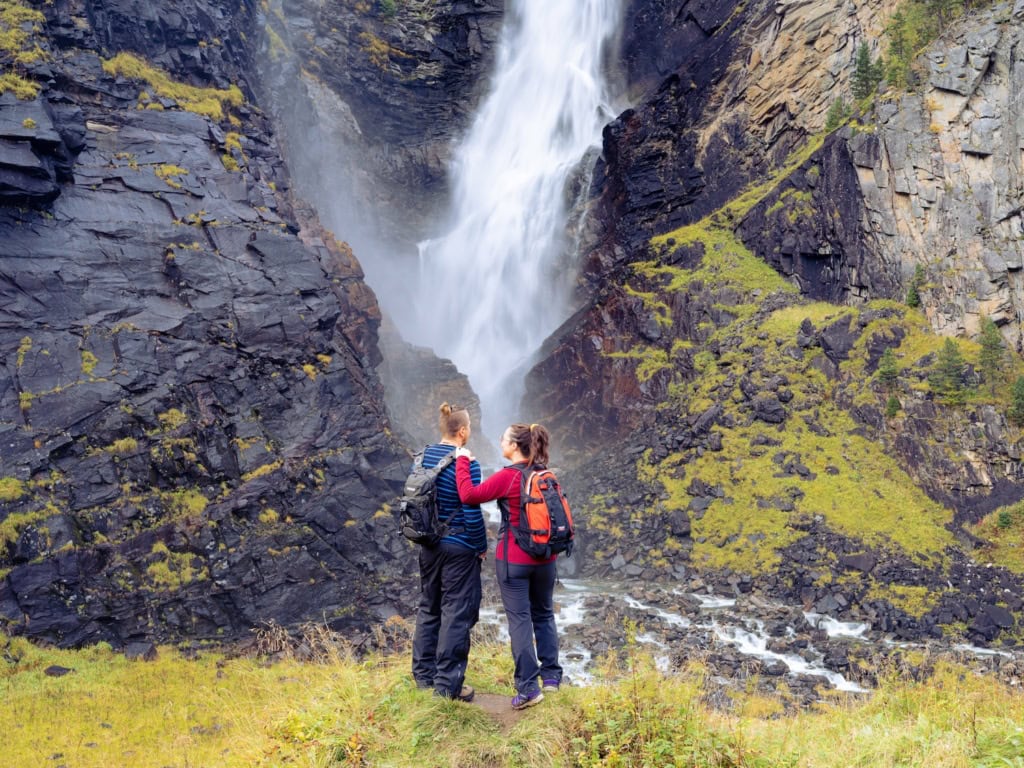 Zwei Personen stehen vor einem Wasserfall in Norwegen