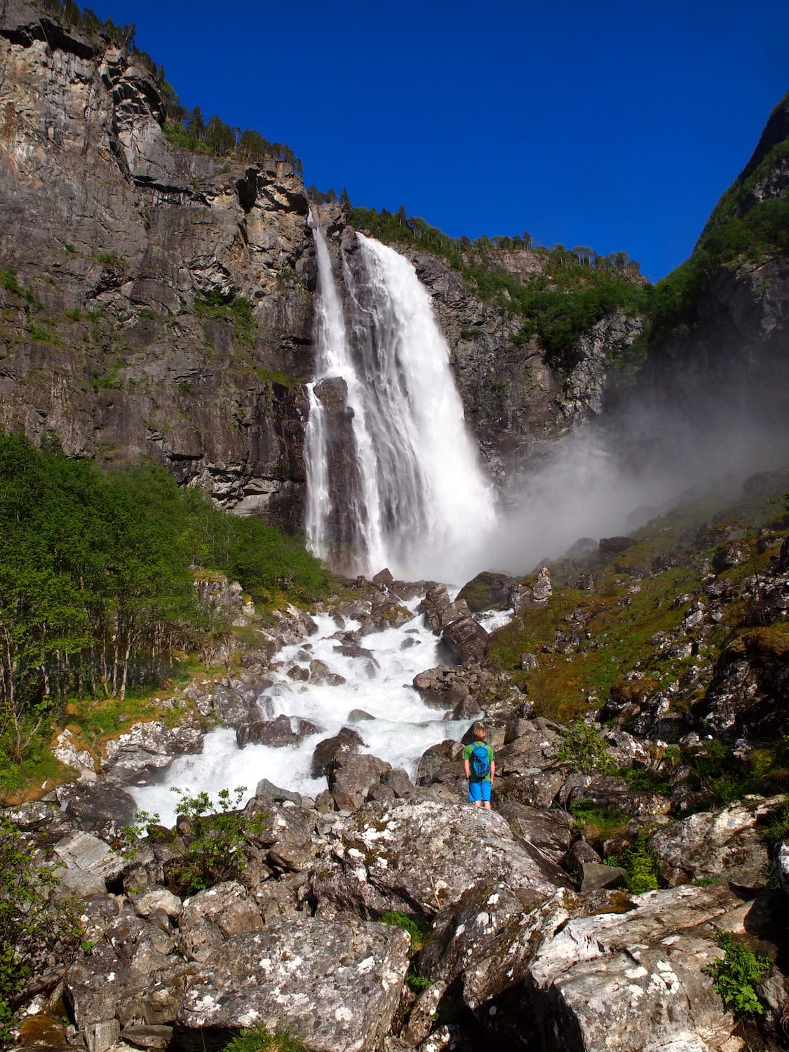 Ein Kind steht vor dem Feigefossen Wasserfall in Norwegen