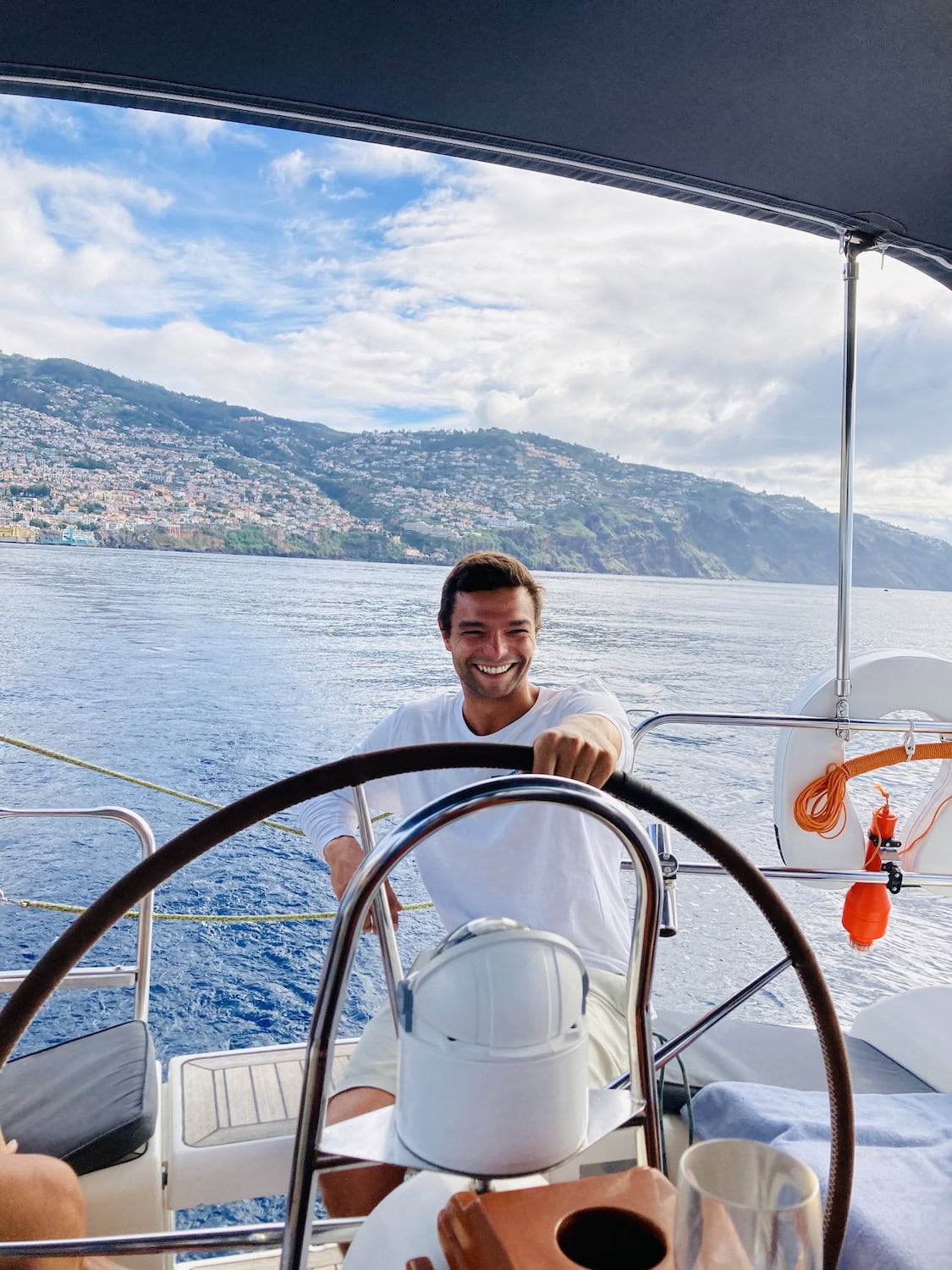 Alex von der Happy Hour Crew auf einem Segelboot am Ruder