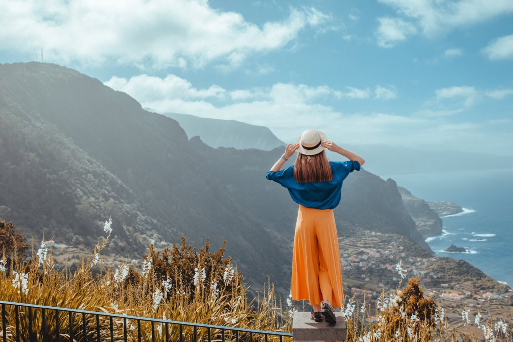 Eine Frau steht auf einem Stein und schaut auf den Ausblick von Madeira