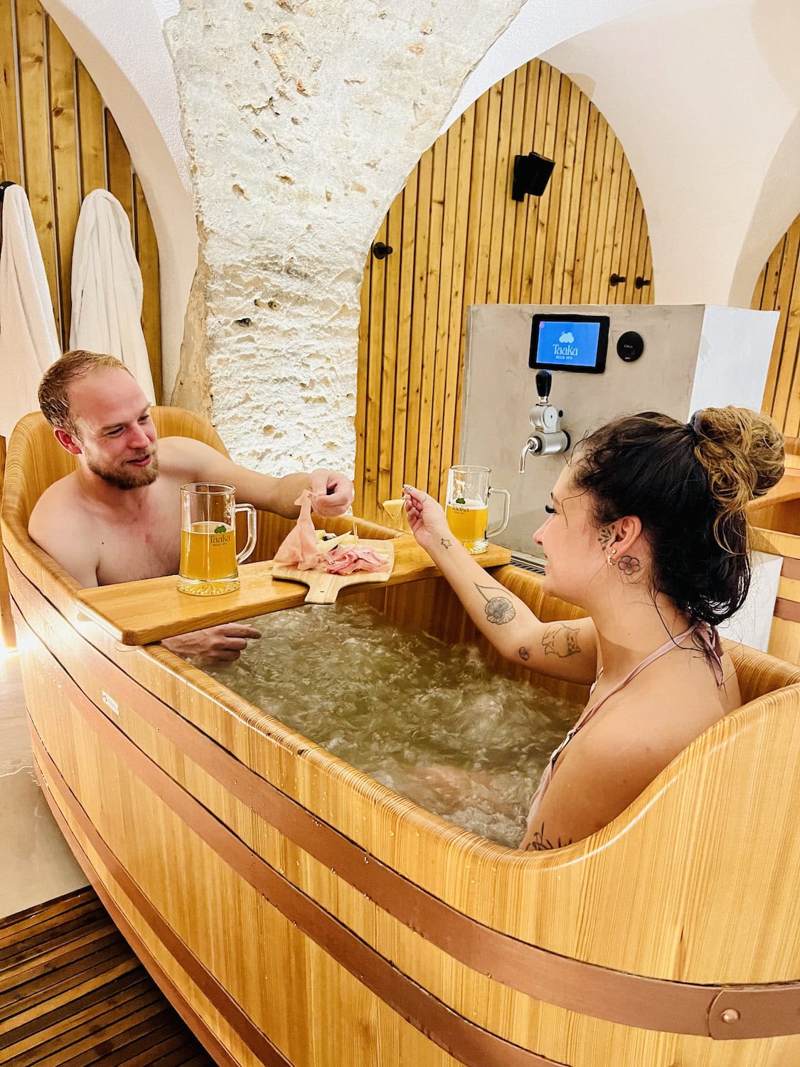 Zwei Personen liegen in einer Badewanne mit Bier und Snacks im Taaka Beer Spa im Elsass