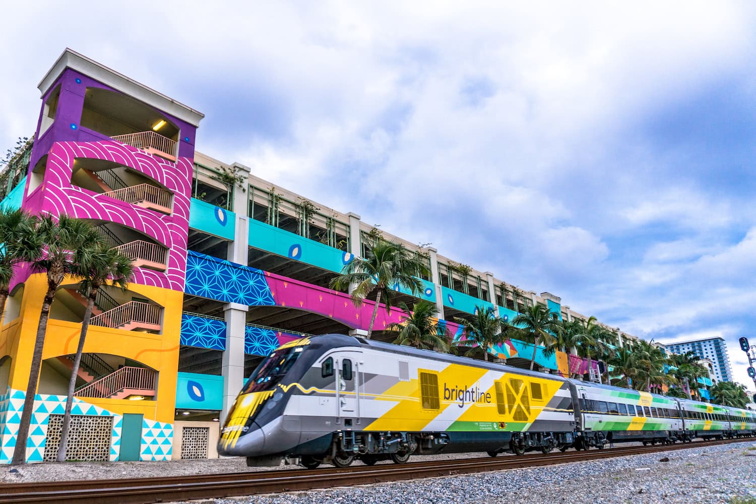 Der Brightline Train vor einem farbenfrohen Haus auf einer Zugfahrt in den USA
