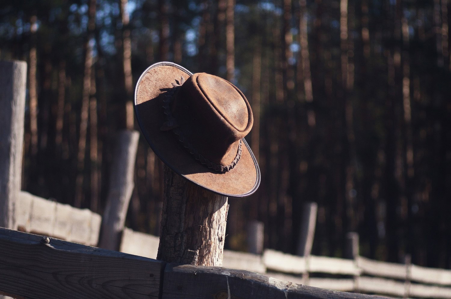 Ein Cowboyhut hängt an einem Holzzaun