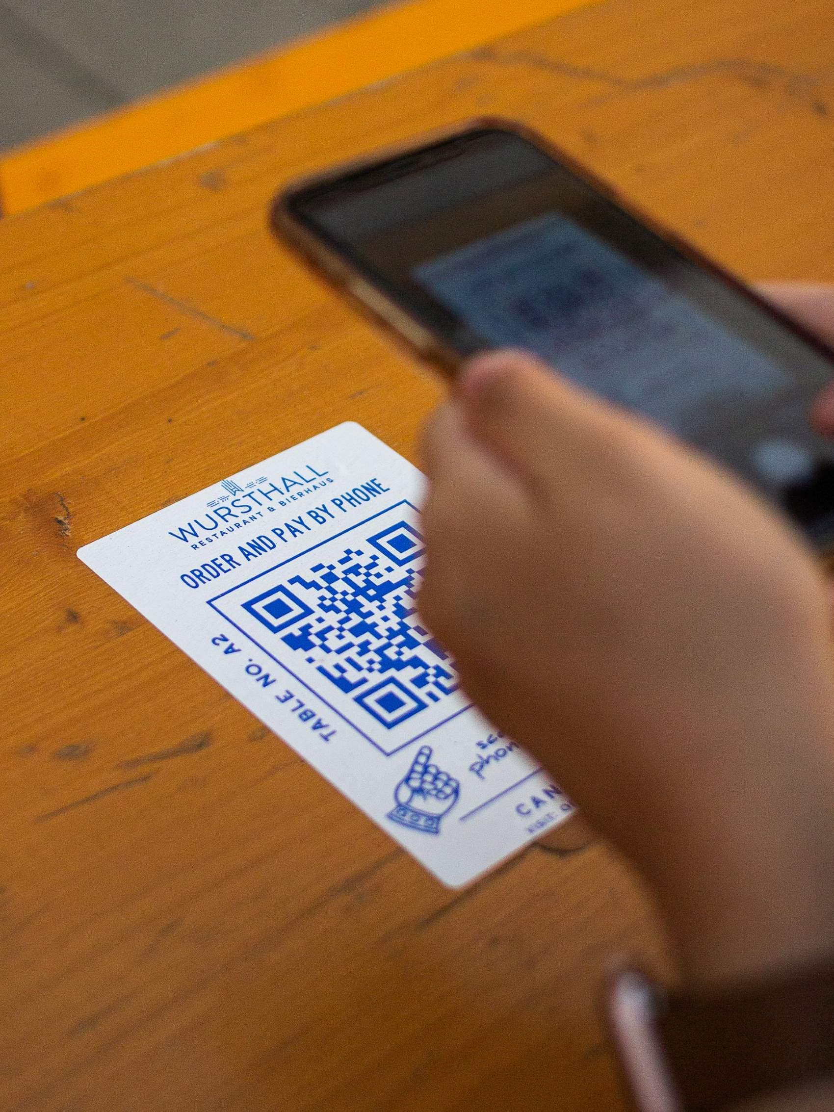 Person scannt mit Handy QR-Code im Restaurant