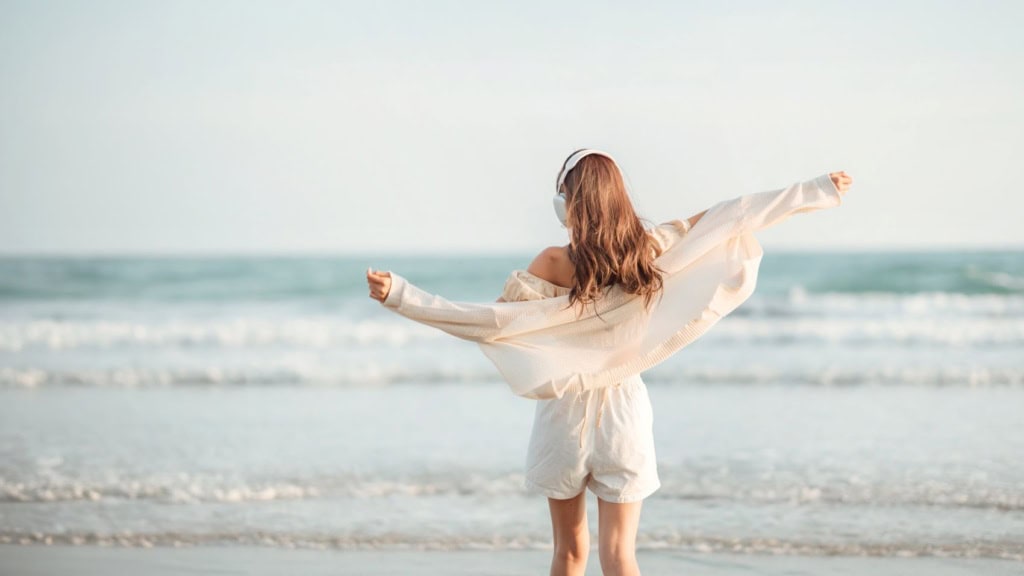 Frau mit Kopfhörern am Strand