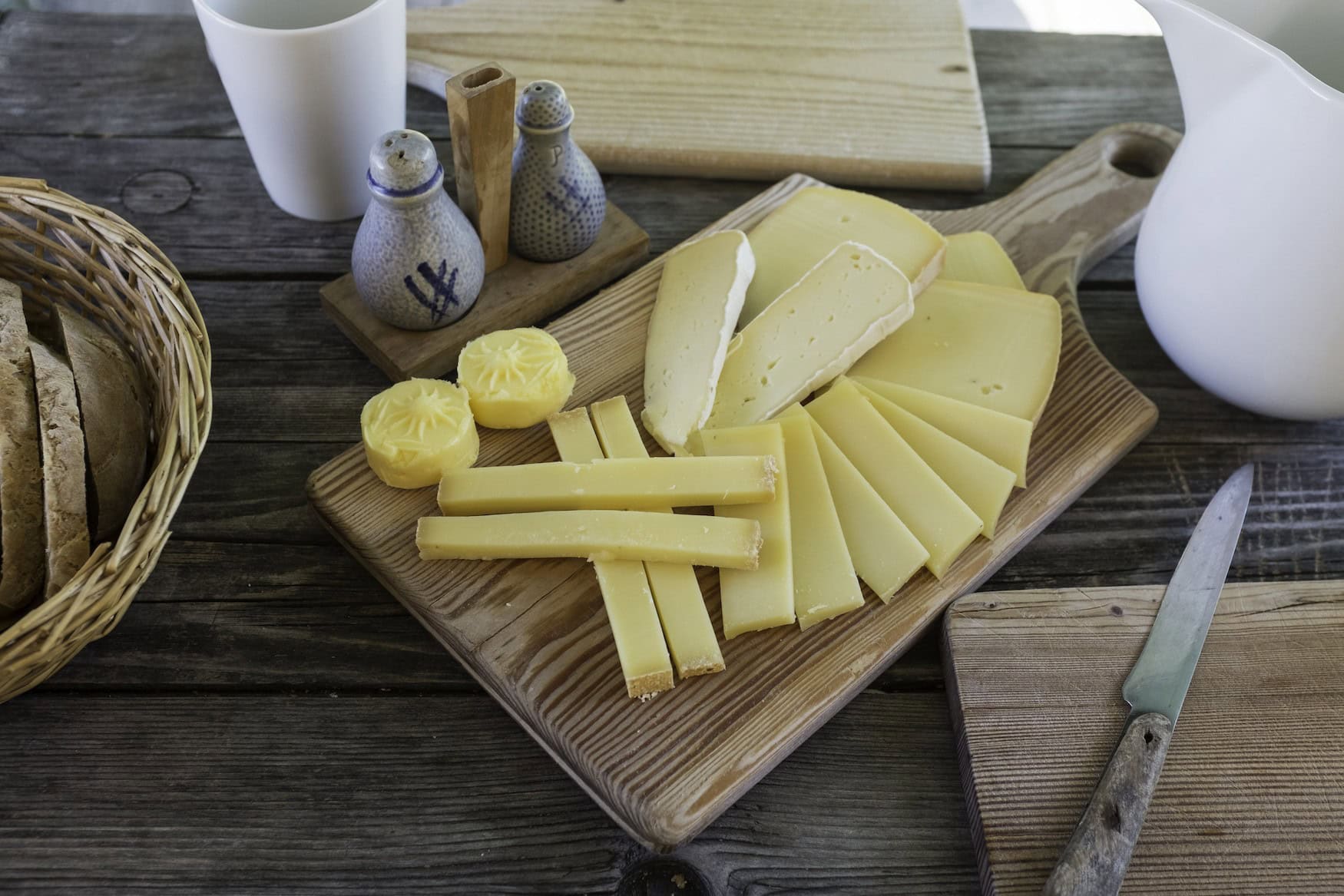 Ein Vesperbrett mit Käse, und an der Seite stehen Brot und Gewürze parat.