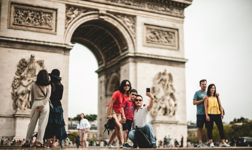 Touristen posieren vor dem Arc de Triomphe in Paris für ein Foto