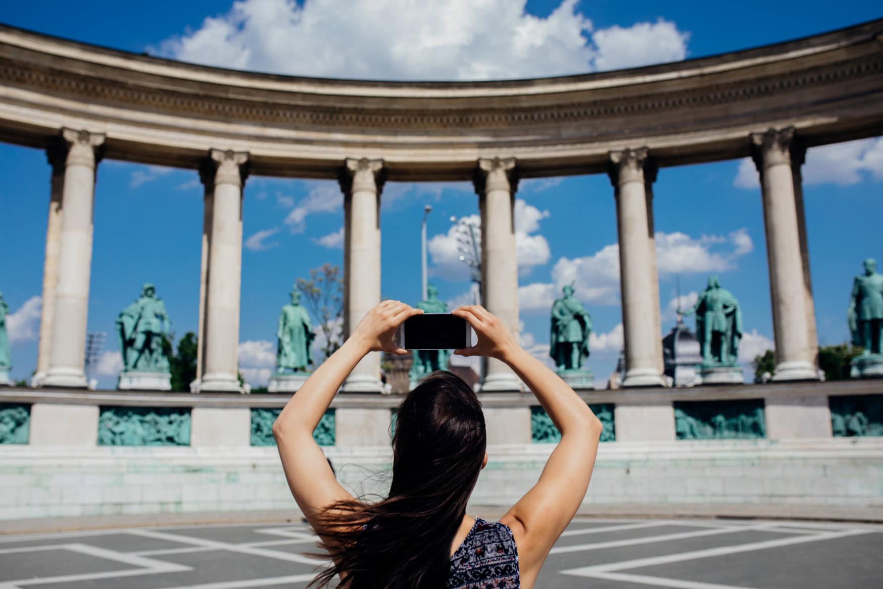 Eine Frau fotografiert einige Statuen am Heldenplatz in Budapest.