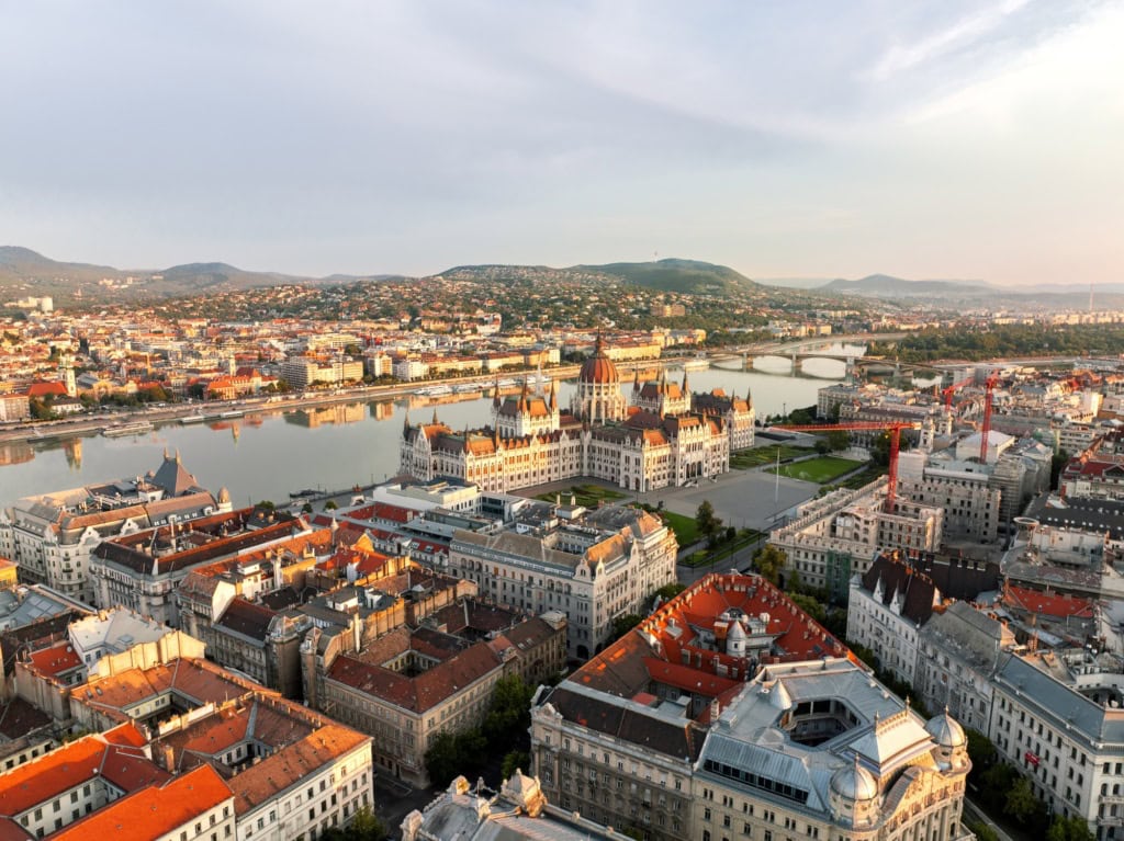 Luftaufnahme von Budapest an einem Sommertag, mit dem gut sichtbaren Parlament im Fokus.