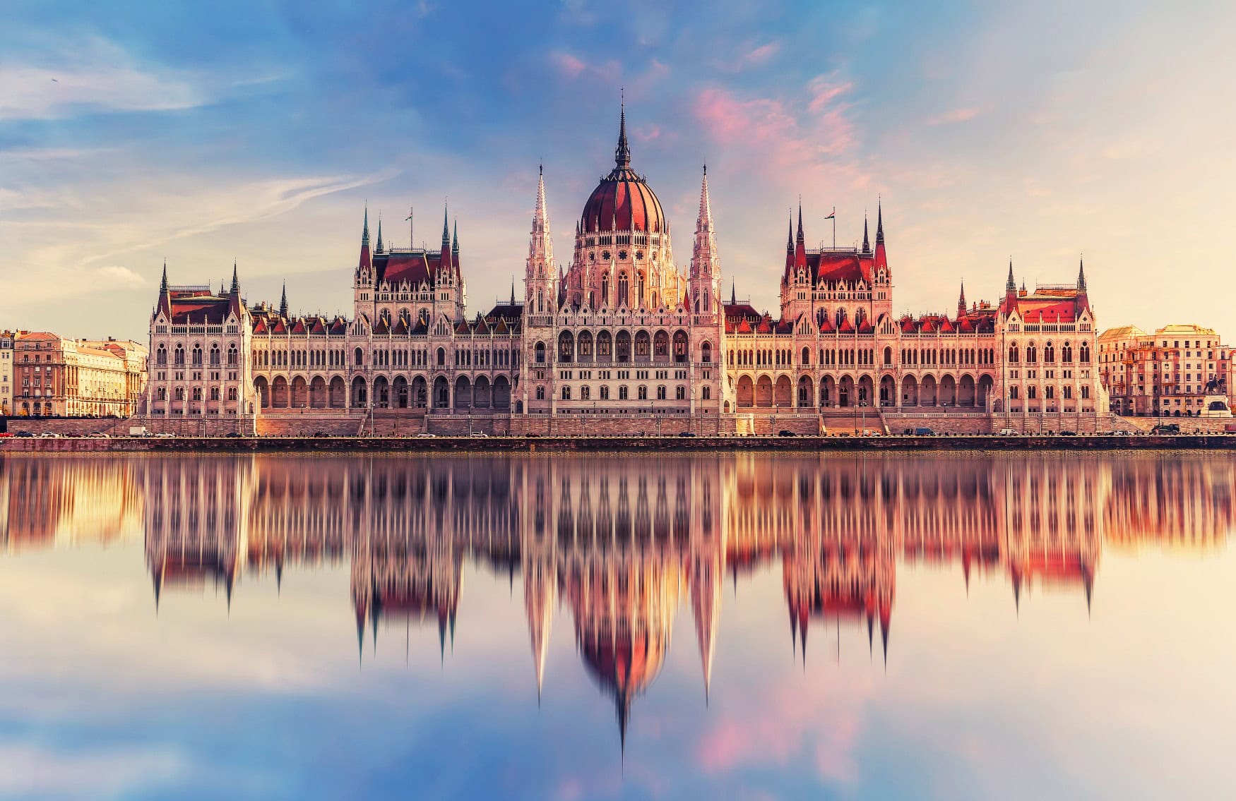 Das ungarische Parlament in Budapest, eine der Sehenswürdigkeiten der Stadt, vom gegenüberliegenden Ufer der Donau aufgenommen. Das Gebäude spiegelt sich perfekt in der glatten Oberfläche des Flusses.