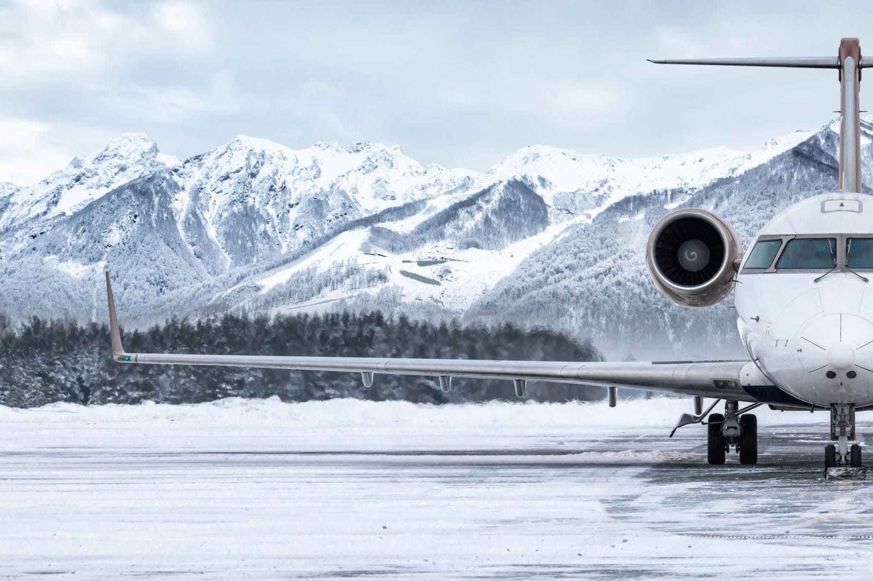 Flugzeug auf schneebedeckter Landebahn, im Hintergrund Berge 