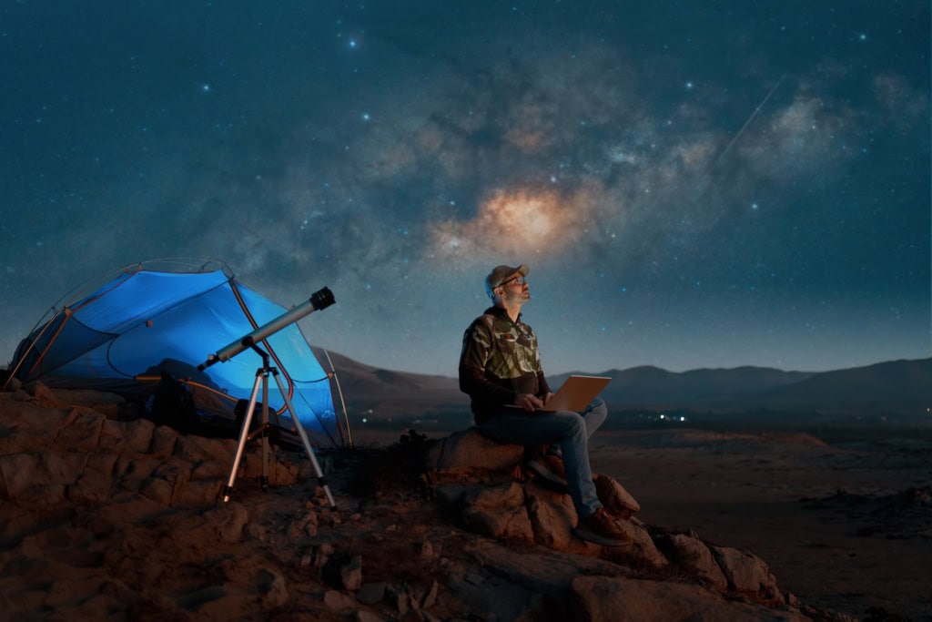 Ein Mann sitzt in der Atacama-Wüste und beobachtet die Sterne.