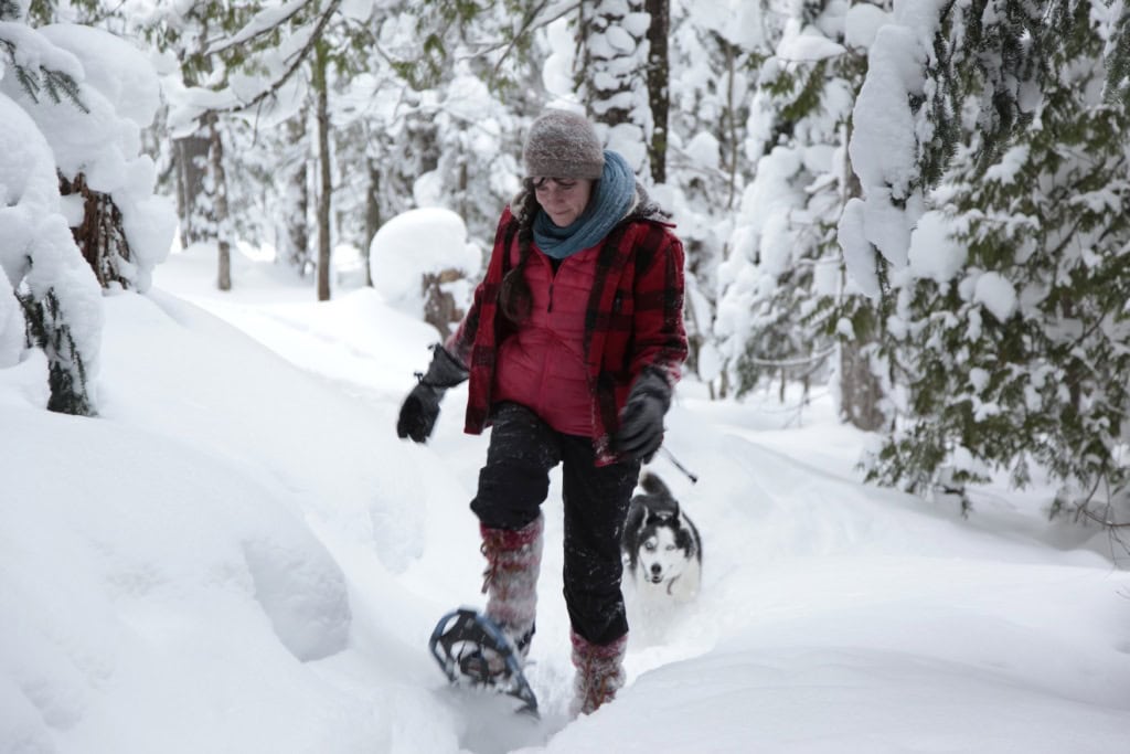 Eine Frau bahnt sich mithilfe von Schneeschuhen ihren Weg durch eine Landschaft in den USA im Winter.